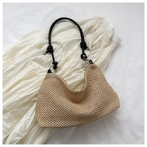 Top view of woven straw tote bag with black rope handles and scalloped edge detail