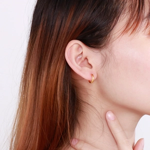 Close-up of minimalist golden stainless steel hoop earring worn on a model's ear