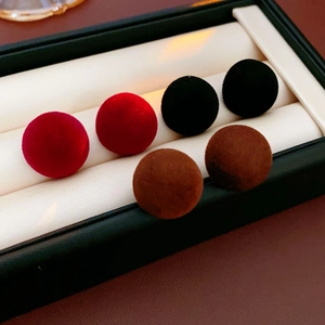 Close-up of velvet flocking ball stud earrings in red, black, and brown displayed in a box