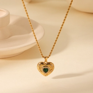 Macro detail of 18K gold stainless steel twist chain and green heart zirconia pendant