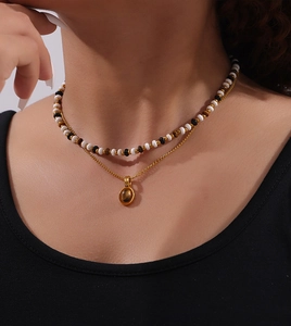 Detail of a layered necklace with natural tiger eye pendant and multi-color beaded strands