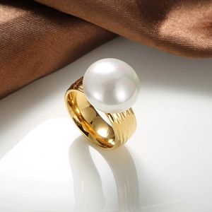 Detail of a golden hammered stainless steel ring featuring a large white round pearl inlay