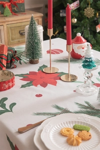 Detailed close-up of a white Christmas tablecloth with red flowers and green pine patterns