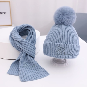 Detailaufnahme von hellblauem Strickset aus Mütze und Schal mit Bärenbestickung