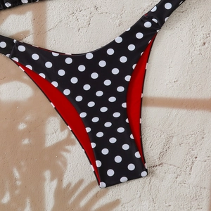 Detailed close-up of polka dot bikini bottoms with red lining and high-cut fit