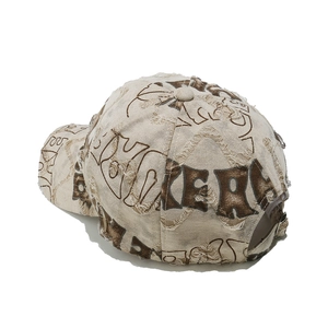 Close-up of distressed beige baseball cap with graffiti prints and metal buckle strap