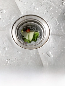Close-up of a white PE mesh sink strainer bag filtering food scraps in a kitchen sink
