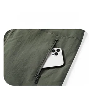 Detail of army green outdoor jacket featuring a secure zippered side pocket with phone