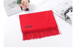 Detail of red cashmere scarf with fringe, featuring a brand label in a stylish setup