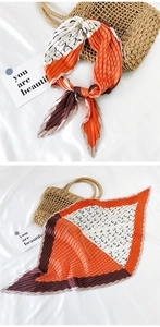 Detail of pleated silk scarf with geometric pattern tied on straw bag handle