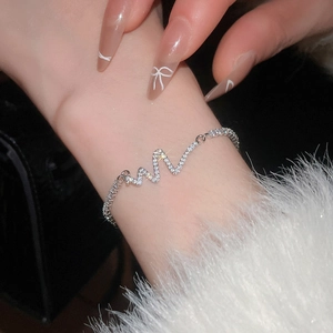 Close-up of silver zircon heartbeat bracelet on wrist with elegant faux fur cuff
