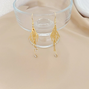 Gold branch earrings with zircon chains draped over glass for a sophisticated jewelry aesthetic