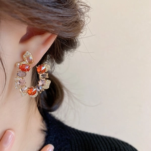 Macro detail of U-shaped gold earrings with colorful zircon stones and fine inlay work