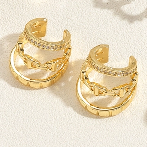 Macro detail of gold-layered ear cuff featuring zircon stones and geometric carvings