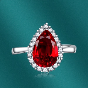 Detailed view of pear-cut red gemstone ring with halo setting on polished metal band
