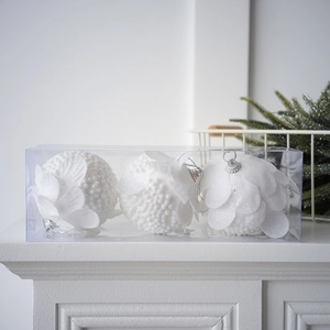 Close-up of three white petal Christmas balls with bead texture in a clear display box