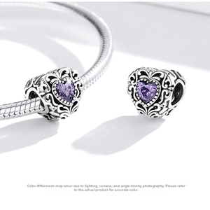 Macro detail of S925 silver purple heart charm with vintage hollow scrollwork on a bracelet