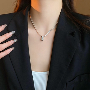 Detail of silver waterdrop pendant on double-layer snake chain necklace worn by model