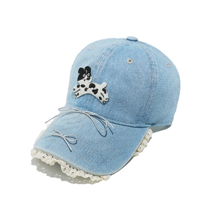 Détail de casquette en jean bleu clair avec bordure en dentelle et broderie de chien