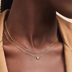 Double-layered gold necklace with blue square zircon pendant on elegant female model