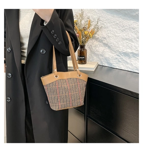 Detail of houndstooth fabric bucket bag with brown leather trim and silver ring hardware