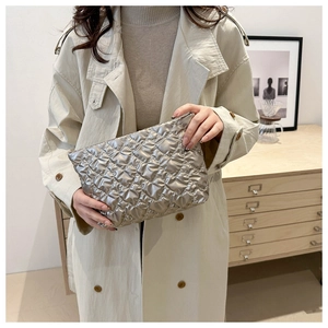 Close-up of a silver quilted cosmetic pouch with a metallic finish held by a model