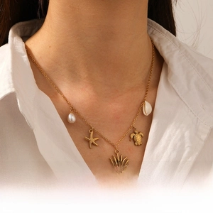 Close-up of gold chain necklace featuring turtle, starfish, sun and pearl charms
