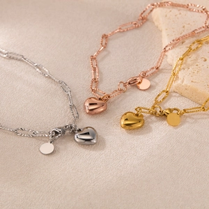 Detailed view of silver, gold, and rose gold heart pendant paperclip chain bracelets