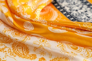 Detailed macro shot showing the silky texture and yellow paisley patterns on the scarf