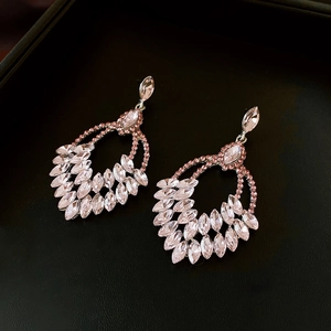 Detail of luxury teardrop fringe earrings with pink crystals on black leather texture