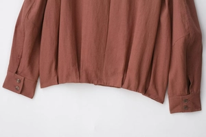 Detailed view of rust red suede jacket cuffs with two-button closure and textured fabric