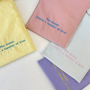 Detail showing four colors of embroidered canvas phone bags with high texture and colorful stitching