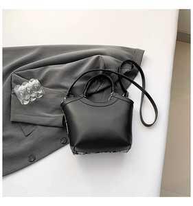 Close-up of matte black leather bucket bag with elegant embroidery and smooth texture