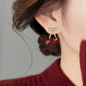 Close-up of model wearing cherry earrings with resin fruit and golden bow details