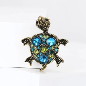 Retro turtle brooch in bronze metal with blue and green rhinestones on white background