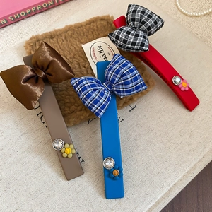 Detailed set of three bow hair clips in brown satin, blue plaid, and red matte textures