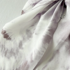 Detailed macro view of purple and white tie-dye chiffon fabric texture and label