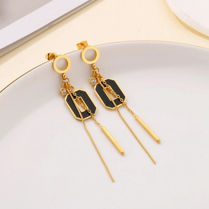 Boucles d'oreilles pendantes dorées et noires avec strass sur un plateau céramique