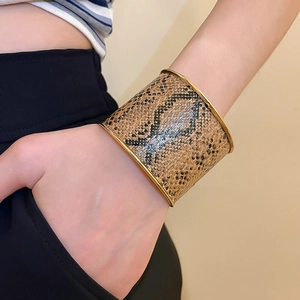 Close-up of wide golden cuff bracelet featuring realistic brown snake skin texture detail