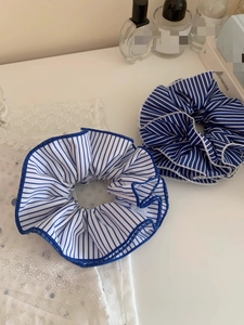 Close-up of blue striped fabric oversized scrunchies for hair styling on white surface