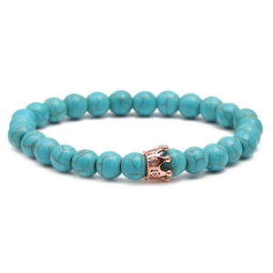 Detail of turquoise beaded bracelet with rose gold crown charm and zircon inlay