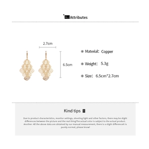 Detail view of gold hollow mesh diamond earrings with copper specs and dimensions