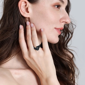 Close-up of black matte wavy ring with 3D sculpted fluid lines on model's hand
