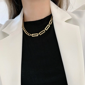 Close-up of a chunky gold titanium steel Cuban link necklace worn by a model