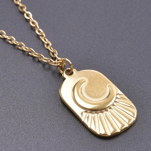 Close-up of gold rectangle pendant necklace with engraved sun and moon rays