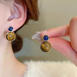 Vintage gold-plated earrings with tiger eye and lapis stones worn by a model