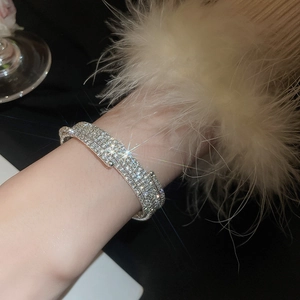Dettaglio del bracciale multistrato in argento con strass e perle sul polso della modella