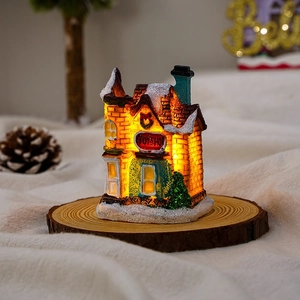 Close-up of a lit resin Christmas TOYSHOP house with snow-covered roof and warm LED glow