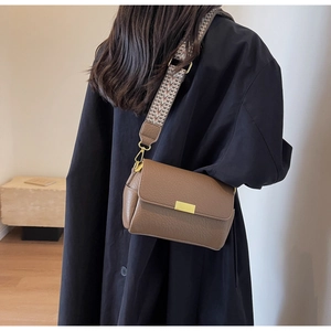 Détail du sac bandoulière en cuir marron avec sangle géométrique et boucle dorée