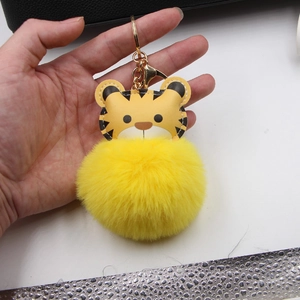 Detail of yellow plush tiger keychain with gold metal ring held in hand by a person
